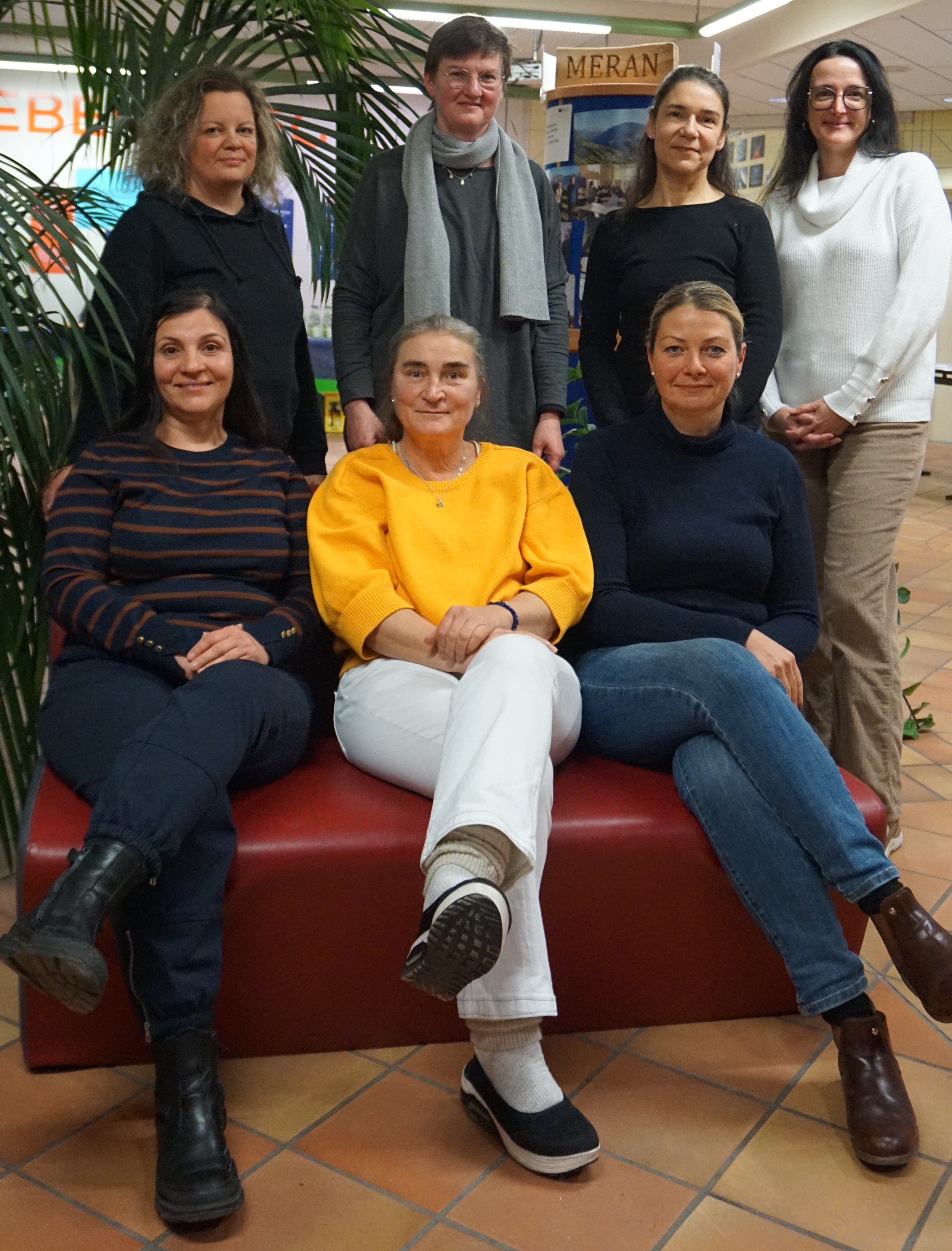 Die aktuellen Mitglieder des Elternbeirates sitzen auf einem Sofa oder stehen dahinter