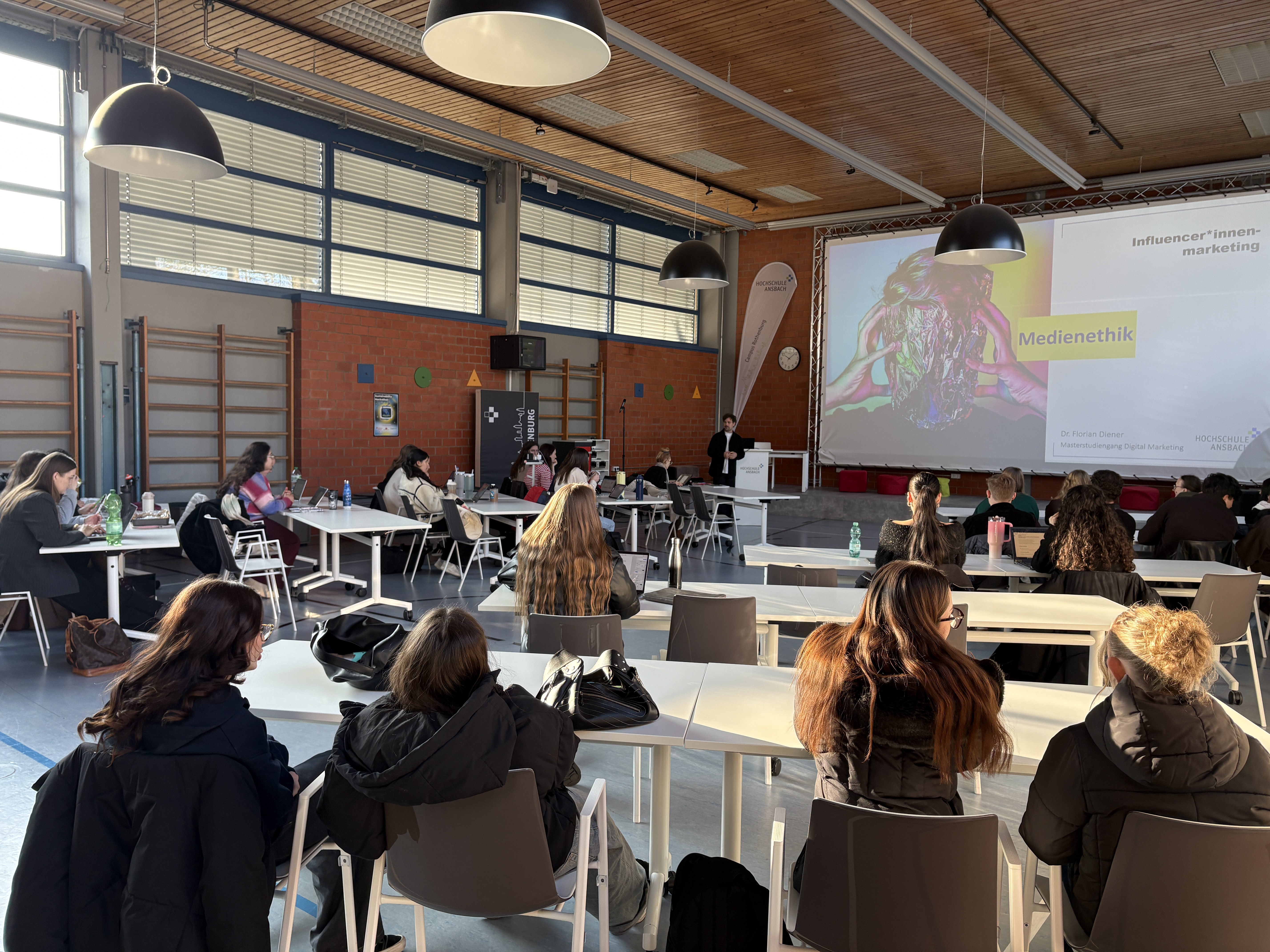 Schüler und Schülerinnen nehmen an einem Vortrag zum Sudiengang Medienethik teil